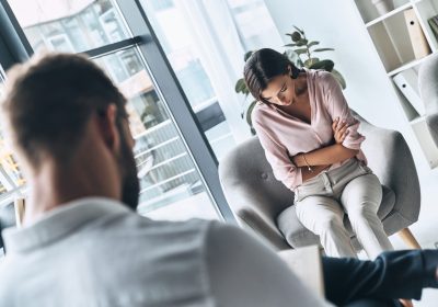 Feeling despair. Young frustrated woman solving her mental problems while sitting on the therapy session with psychologist